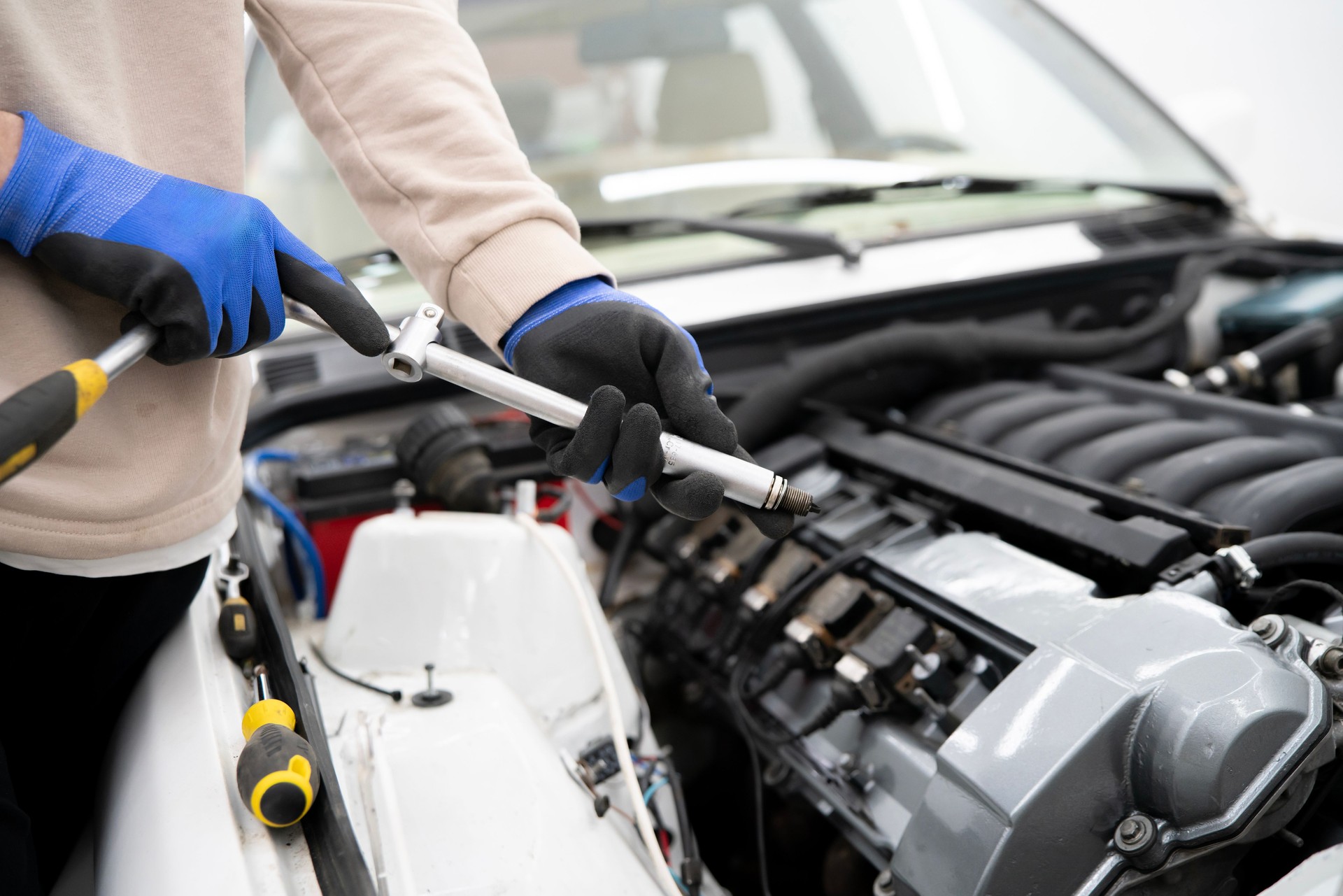Car Mechanic Utilizes Spark Plug Wrench for Efficient Engine Maintenance in a Professional Workshop Setting